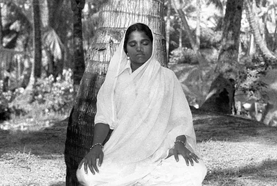 Amma joven meditando bajo un cocotero