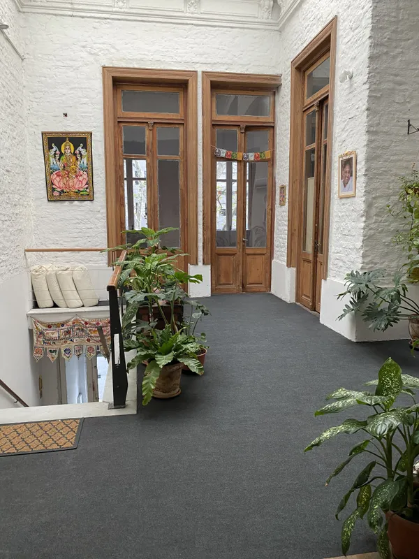 Entrada del espacio: puertas de madera, plantas y banderas de oración